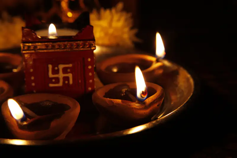 Lit clay diyas on a puja thali