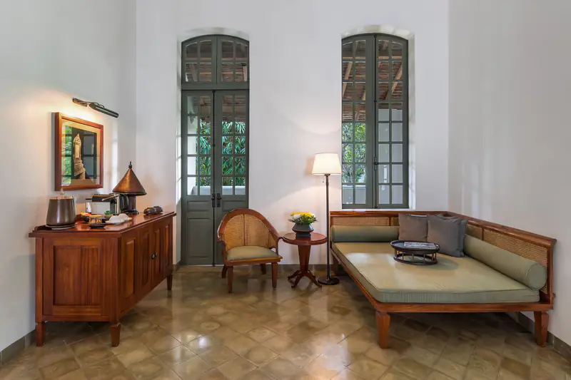 Bright heritage-style hotel room with a daybed and tall arched windows