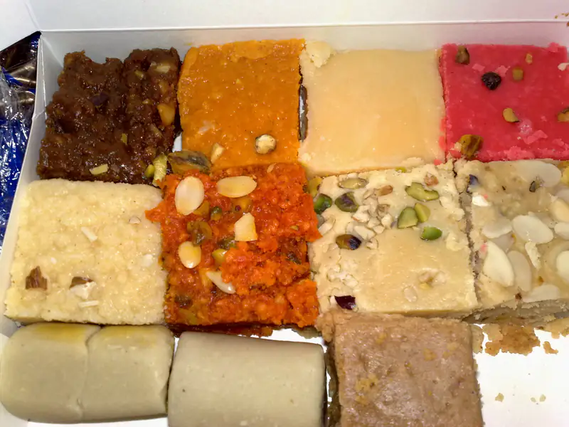 Box of assorted Indian sweets topped with almonds and pistachios